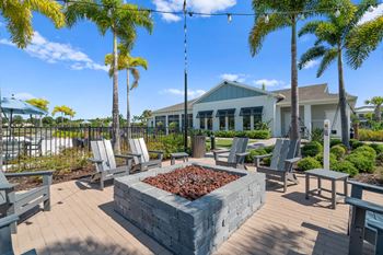 a patio with chairs and a fire pit and a building in the background